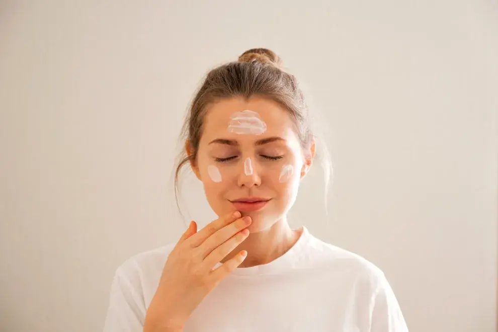 Una mujer aplicandose crema en la cara