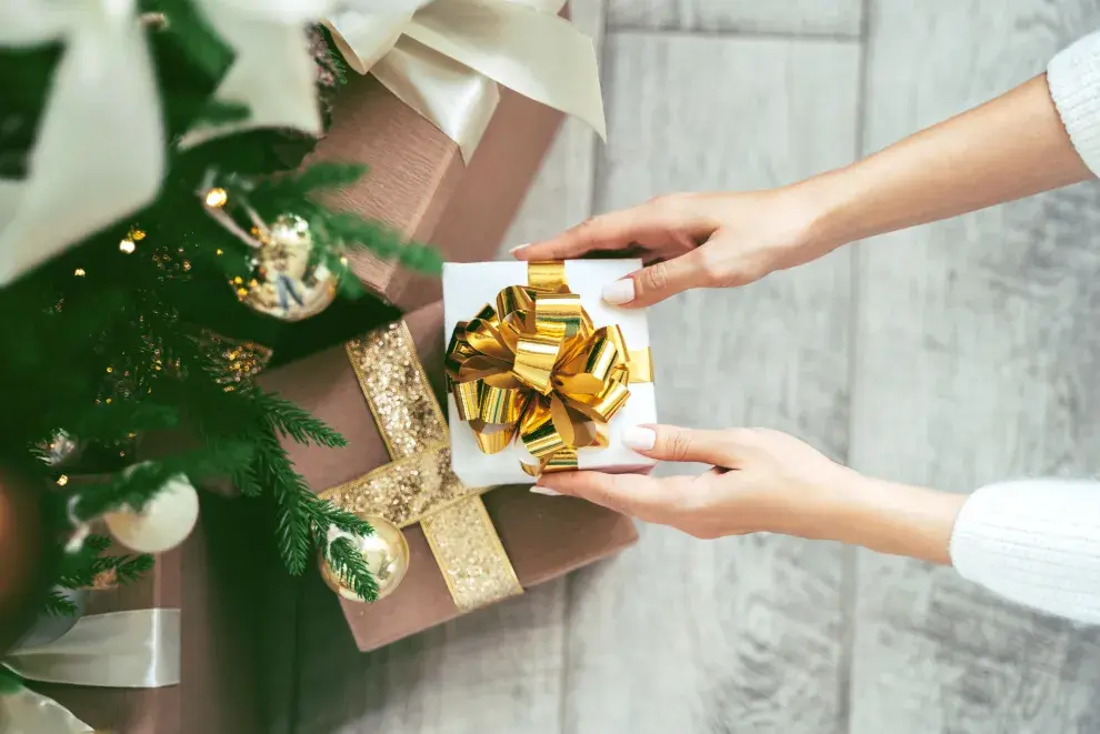 Mujer ordenando los regalos en el árbol de navidad