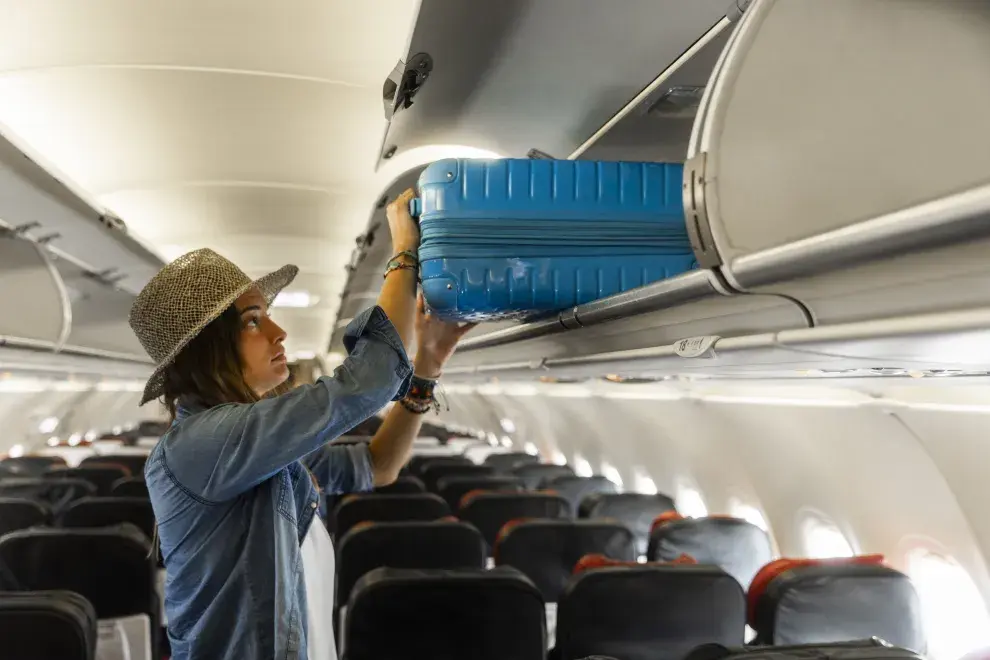 Una mujer con un carry on en el avión