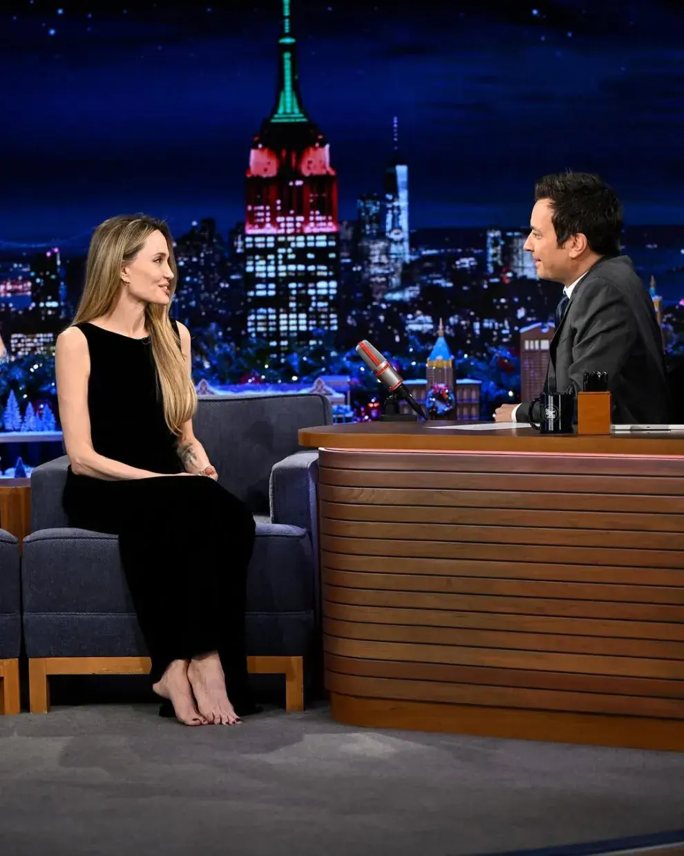 Foto de Angelina Jolie descalza, siendo entrevistada por Jimmy Fallon.