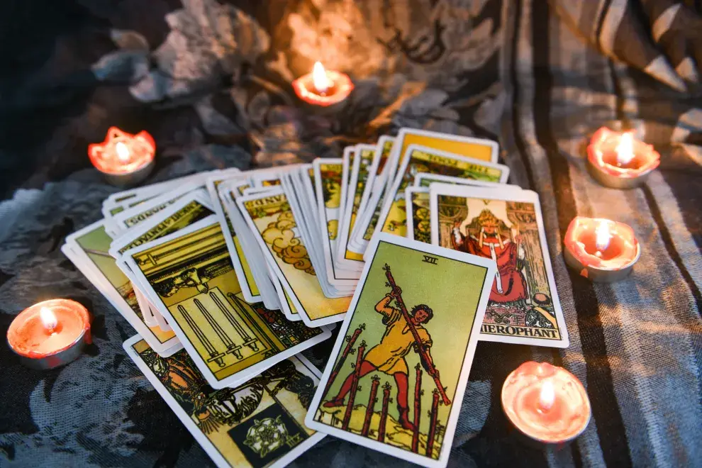 Un mazo de tarot sobre una tela y unas velas encendidas.