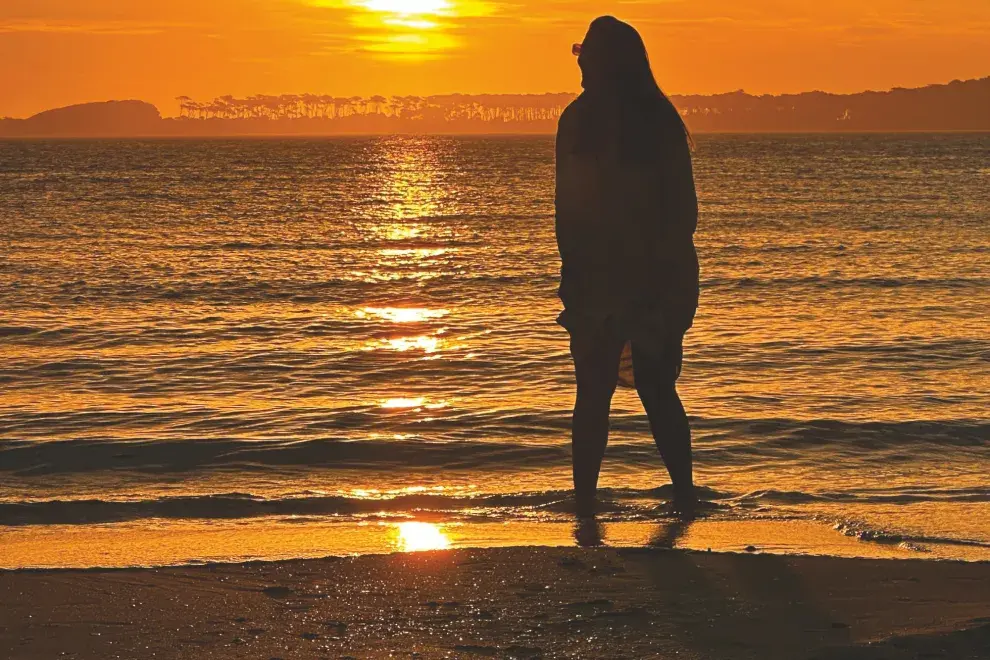 Una chica entrando al mar en un atardecer.