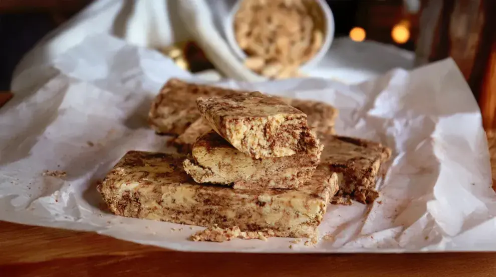 Pilas de trozos de mantecol con chocoalte sobre un plato y papel manteca