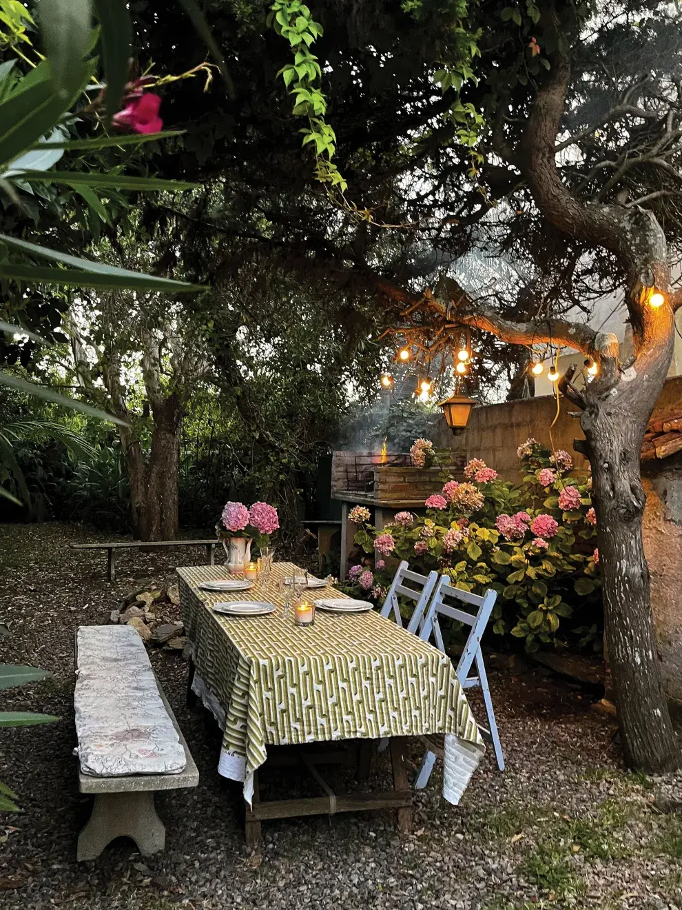 Banco de piedra, sillas pintadas, mantel con estampado pop, la infaltable guirnalda de luces y hortensias en flor: sencillez con mucha onda. 