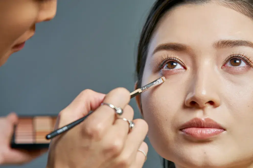 una mujer poniendose corrector de ojeras