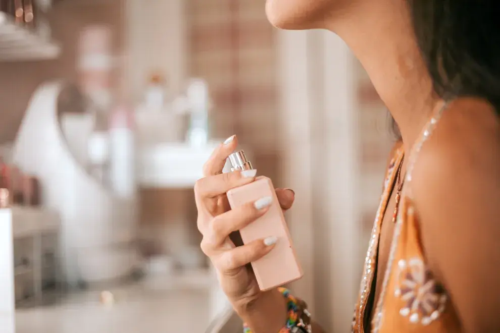 Una mujer poniéndose perfume en el cuello