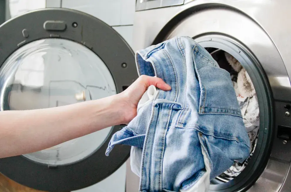 una mujer sacando jeans del lavarropas