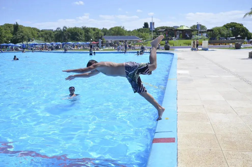 Joven tirandose de cabeza a una pileta pública en Parque Chacabuco