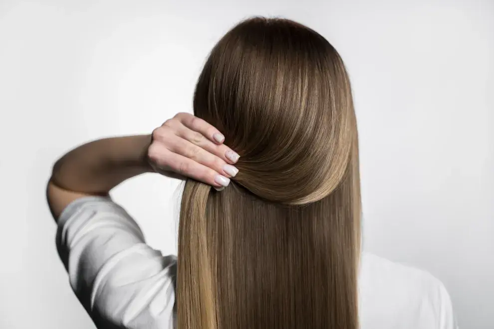 Chica de espalda sosteniendo su pelo hacia un lado dejando ver la cortina de cabellos