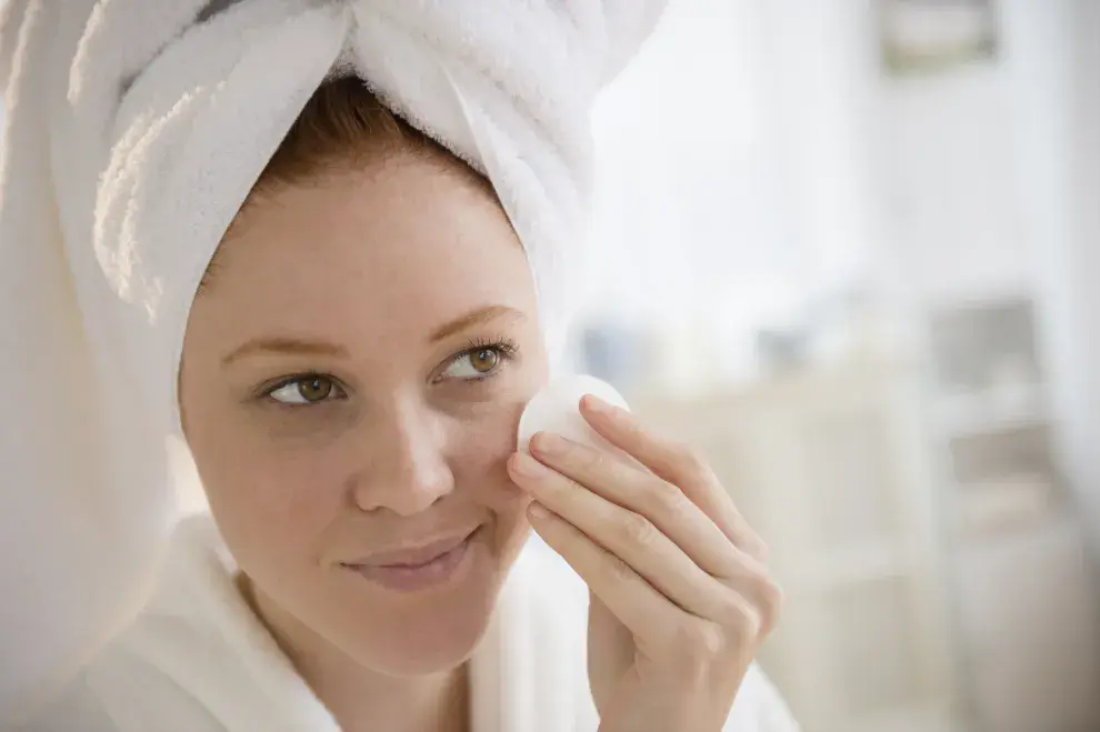 Una mujer haciéndose el skin care frente al espejo