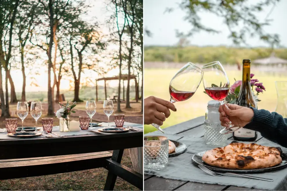 Mesa al aire libre y brindis de una pareja con copas de vino.