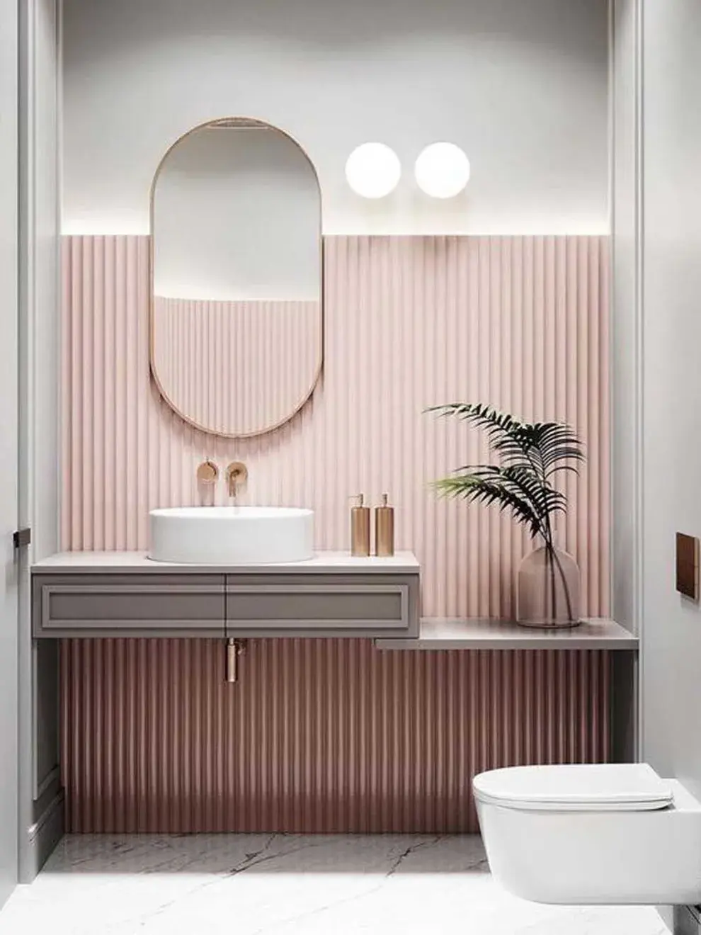 Un baño con espejo ovalado, pared en color rosa y muy poco mobiliario