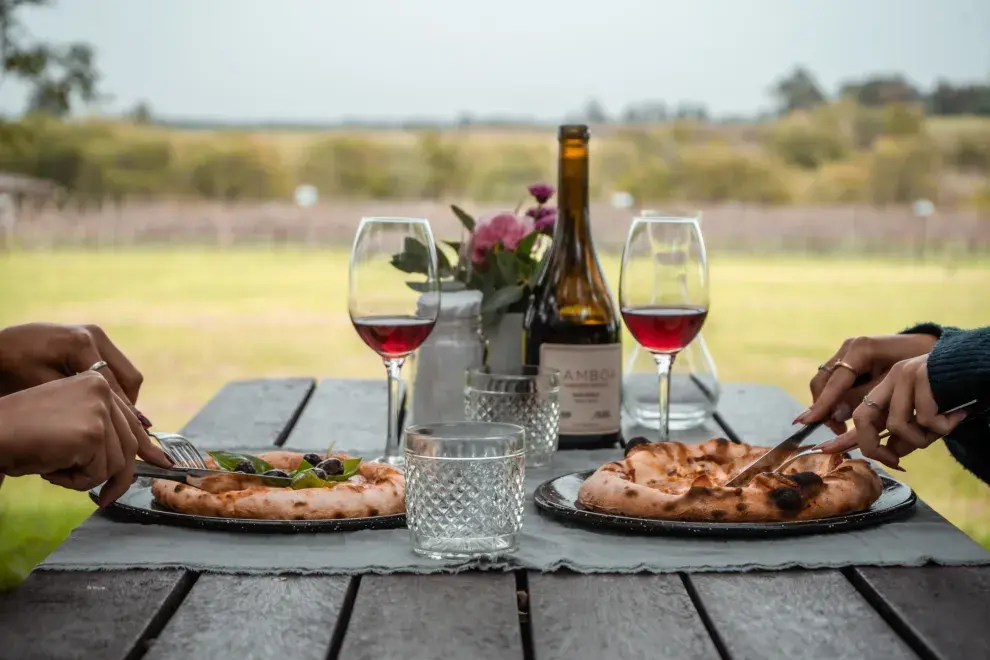 Una mesa con pizzas y vino.