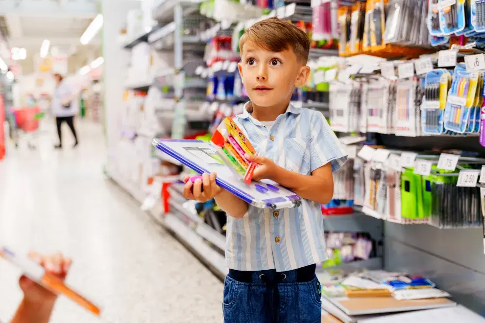 niño comprando útiles escolares con un adulto