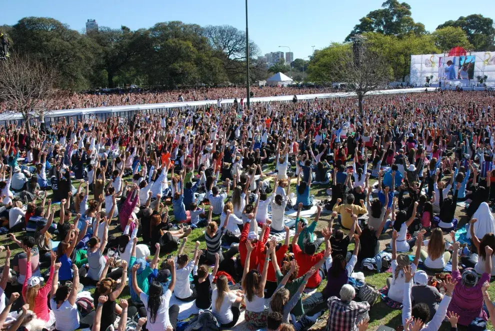 Muchas personas meditando juntas al aire libre.