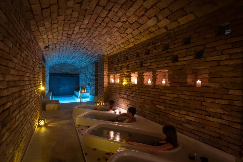 tres personas sumergidas en bañaderas en un spa subterráneo.