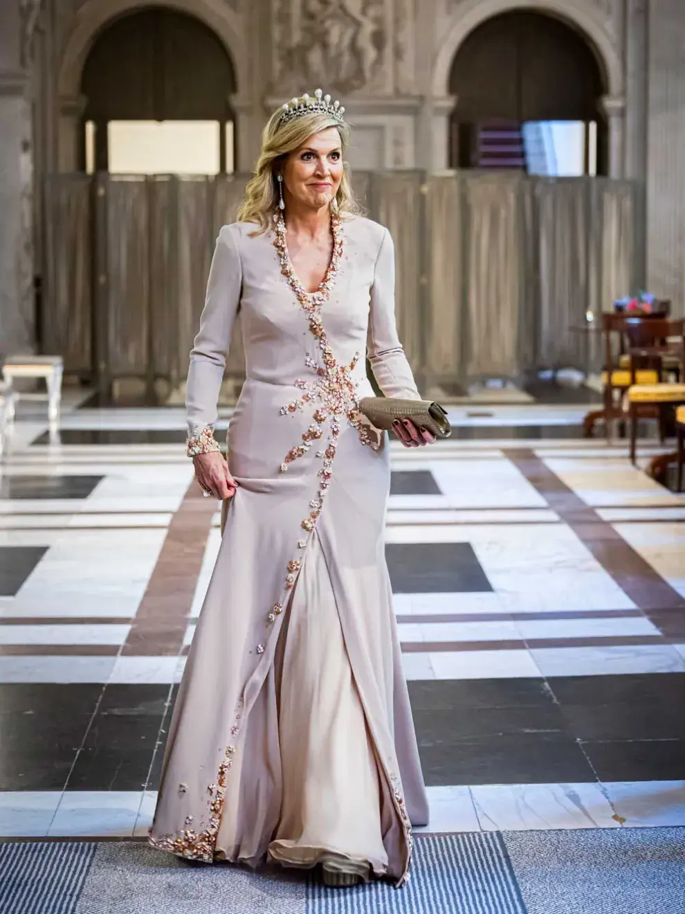 El vestido era cruzado de manga larga en color rosa pastel con un distinguido bordado de piedras doradas y blancas