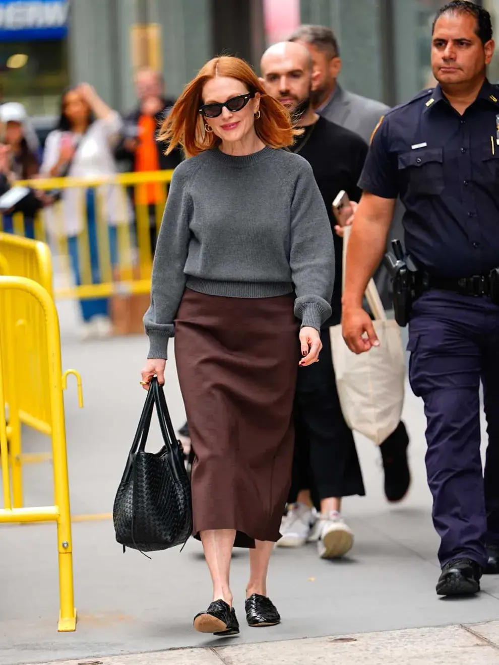 El estilismo de Julianne Moore está formado por una falda midi en color marrón, un jersey básico con cuello redondo y de punto en color gris y los mencionados dos accesorios, todos de Bottega Veneta