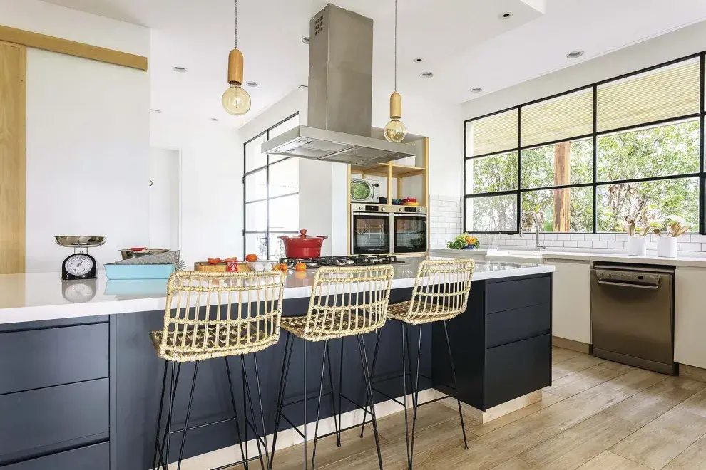 Isla central laqueada (HPS Design, Fabián Portal) con anafe y mesada de Silestone en ‘WhiteStorm’. Banquetas de mimbre (Brugués Mosconi).