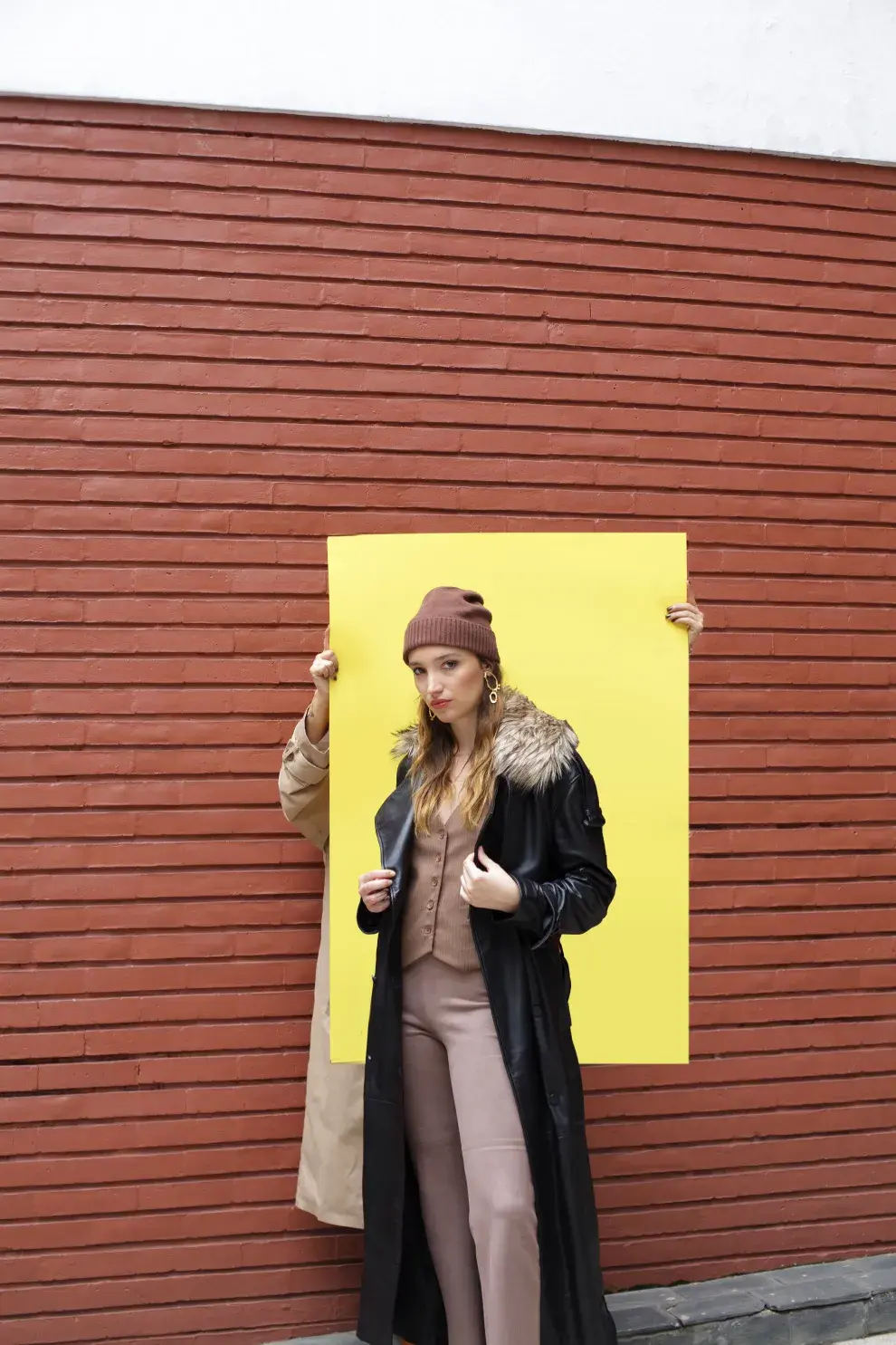 TRENCH NEGRO DE CUERO CON CUELLO DE PIEL DESMONTABLE (TOVAL, $1.890.000), CHALECO SASTRERO, PANTALÓN PESCADOR GAMUZADO Y GORRO DE CACHEMIRA (AWADA, $250.000, $150.000 Y $70.000), BOTAS DE GAMUZA CON TACHAS GRISES (TOVAL), AROS (MECHI GARAY, $39.200).