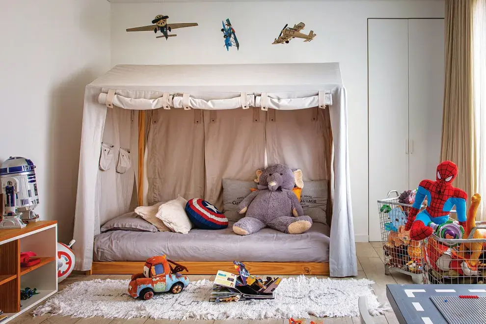 Aviones colgantes, elefante de peluche (Jumbo), cama con dosel (todo de Restoration Hardware), almohadones y alfombra ‘Rayuela’ (todo de Rancho).