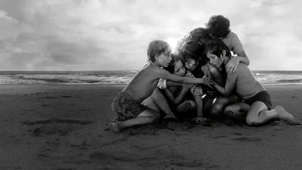 Una mujer abrazada por un grupo de niños en la playa.