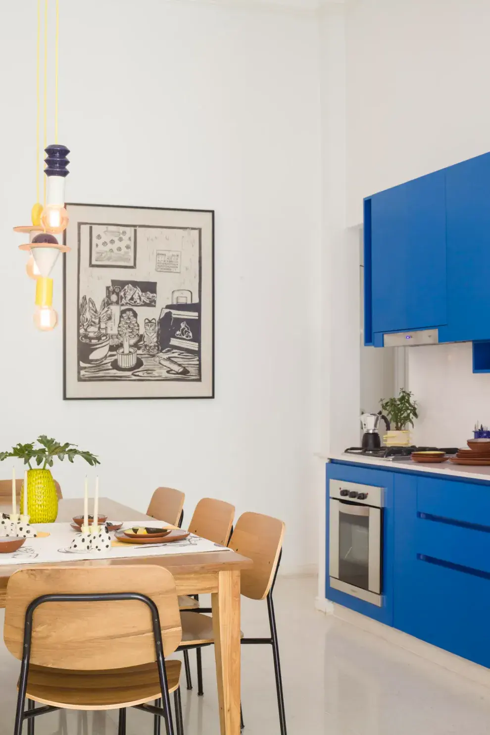 Cuadro de Carolina Bozzano, comprado en la tienda de arte y diseño Somos Yunta, detrás de la mesa (Talleres Sustentables) con sillas de Estudio Te. Lámpara colgante (Casa Sud).