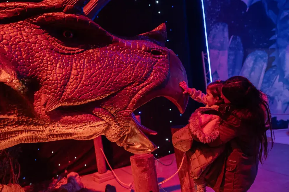 Una mamá y su hija tocando a un dinosaurio