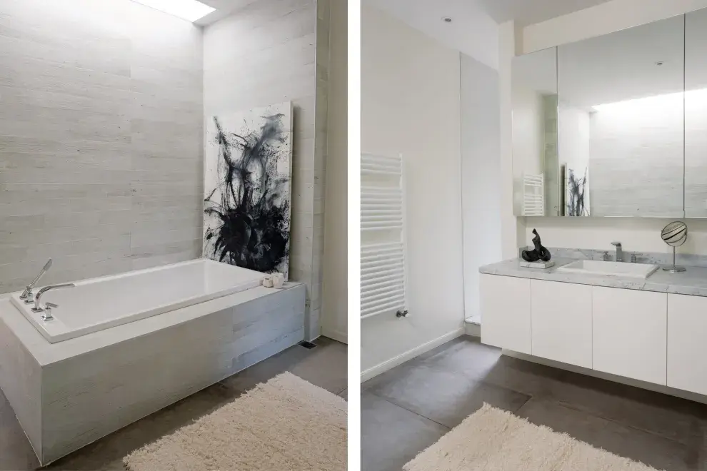 Una claraboya lleva luz natural a la bañadera con revestimiento de porcelanato cementicio. Espejo con botiquín embutido.Acrílico de Rodrigo García Berro.