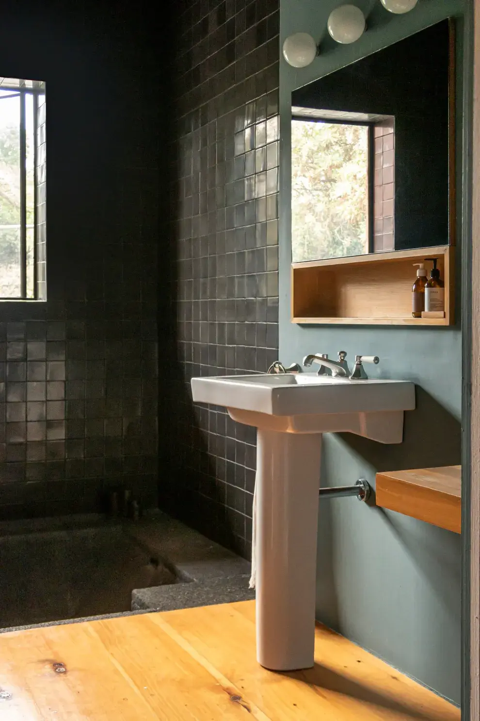 En el baño principal, una bañadera de roca volcánica se acompañó de talaveras negras: un marco teatral para la ventana que mira al jardín. 