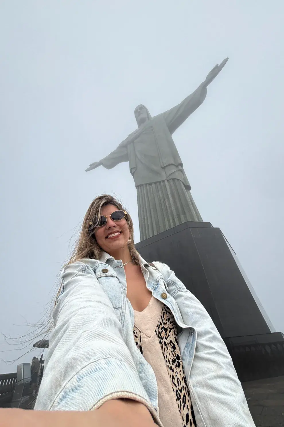 Una mujer sacándose una selfie en un Cristo Redentor.