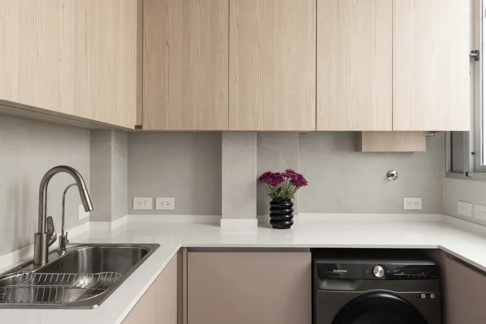 Las alacenas retoman el lenguaje del mueble del comedor realizado en melamina simil madera. Sobre el lavarropas, se oculta la caldera. Mesada es Silestone y grifería de Ponthus.