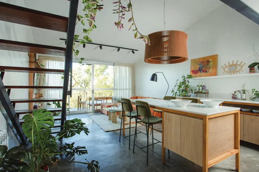 La isla con mesada de cuarzo ‘Calacatta’ y el mueble de madera maciza con frente de melamina ‘Kendal’ (Egger) convirtieron el espacio de comedor en una gran cocina abierta.