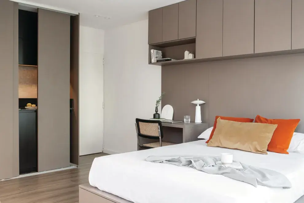 Para una lectura continua, las puertas corredizas que ocultan la cocina se hicieron en el mismo material y color que el escritorio, la cama con cajones y el mueble colgante