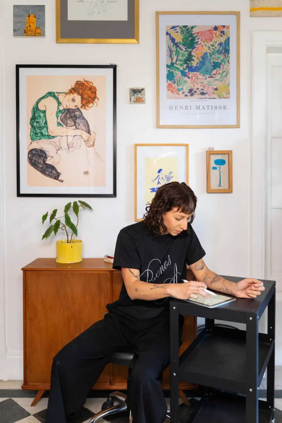 EN EL INGRESO AL DEPARTAMENTO HAY UN ÁREA PEQUEÑA QUE CONECTA TODOS LOS AMBIENTES DE LA CASA. RODEADA DE PLANTAS Y ARTE, ES EL RINCÓN QUE ELIGE PARA TATUAR. 