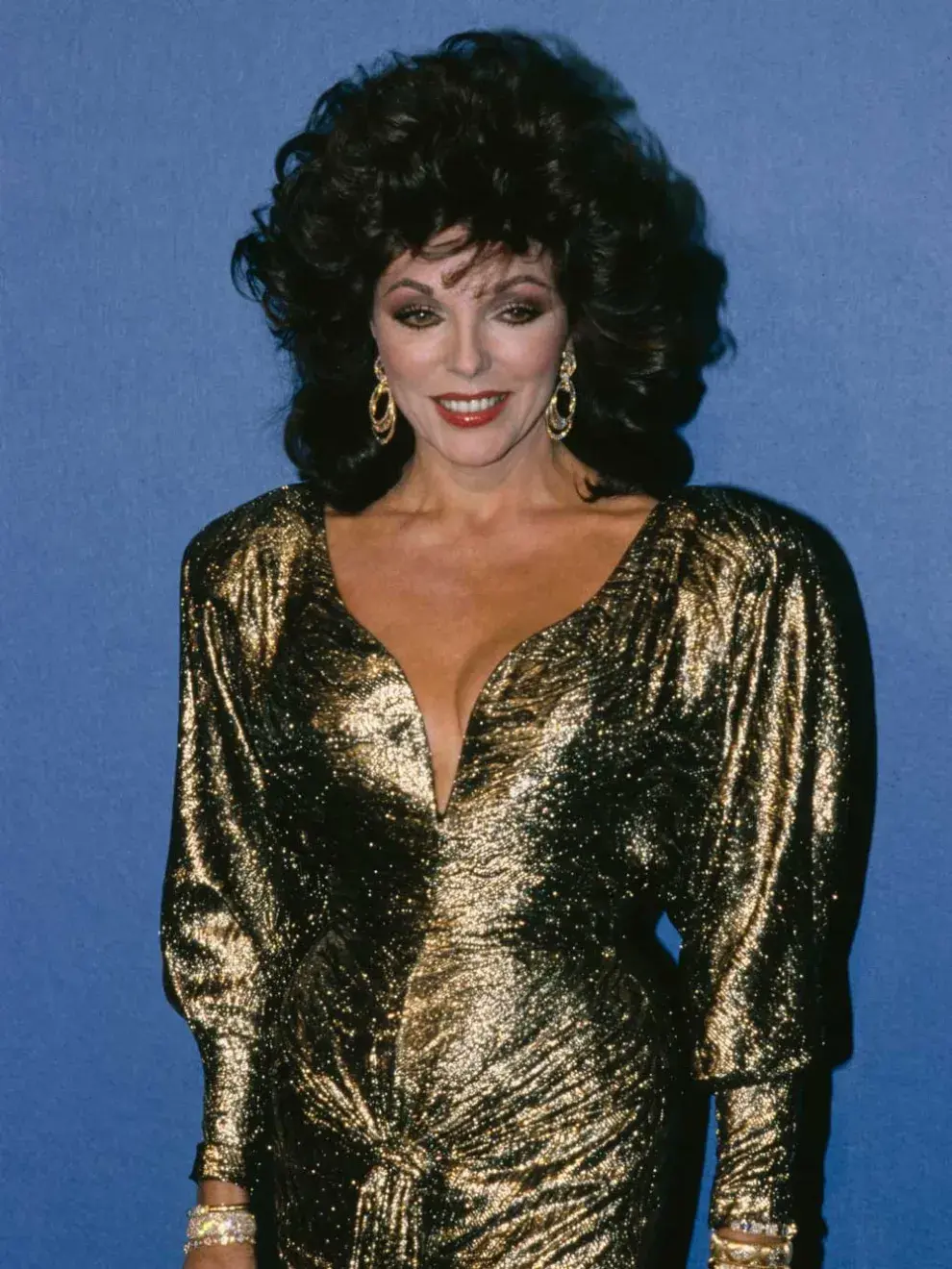 Joan Collins, 1986 Un clásico de los ’80: vestido dorado con hombreras marcadas (“shoulder pads”) y escote tipo corazón.