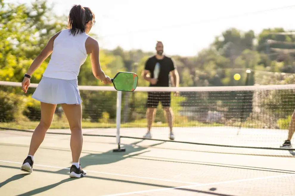 Una cancha de pickeball y dos personas jugando.