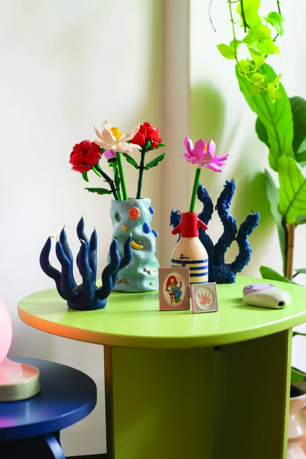 Datazos: mesita verde (@estudio.te), sifón florero (@art.bytina), velas modeladas a mano (@particula.tienda), florero de cerámica (@conimarchini) y minirretratos (@vevucoco). Detrás, el verde de sus plantas.