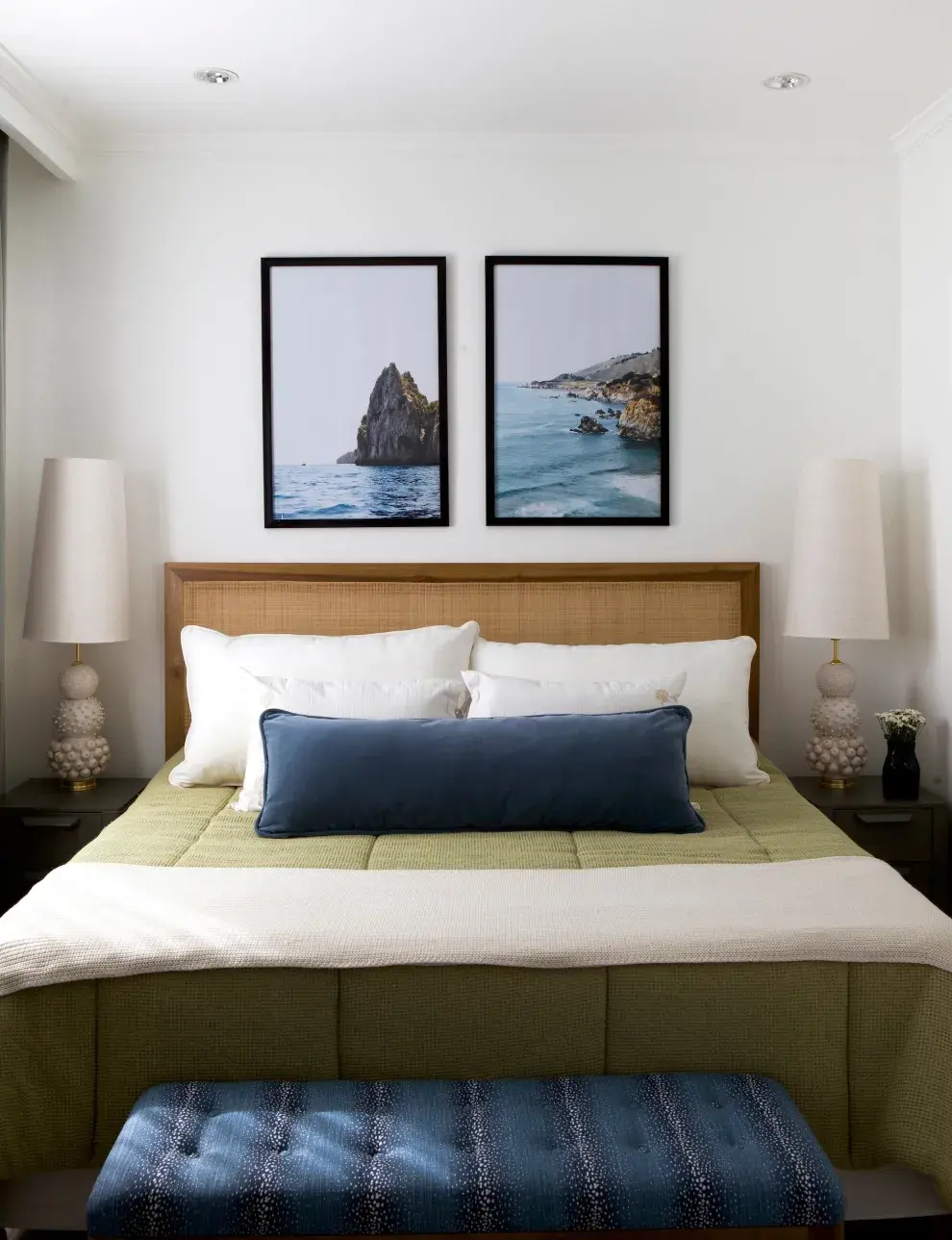 Lámparas de mesa ‘Elba’, con base de cerámica texturada, aportan altura y textura sobre mesas de líneas simples. Encima del respaldo de la cama, las fotografías de la serie 'Playa' enmarcan la escena y suman profundidad visual.