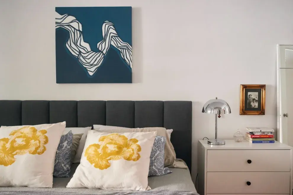 Lámpara cromada de Concreto Art. Respaldo de cama y cubrecama de Innovar Decoraciones.