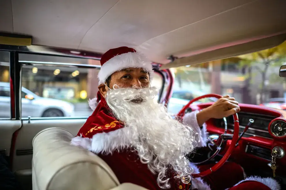 Hiroyuki Wada, miembro de un grupo de coches antiguos, vestido como Papá Noel, conduce su Cadillac de 1959 antes de entregar regalos de Navidad al público en una calle del área de Marunouchi en Tokio