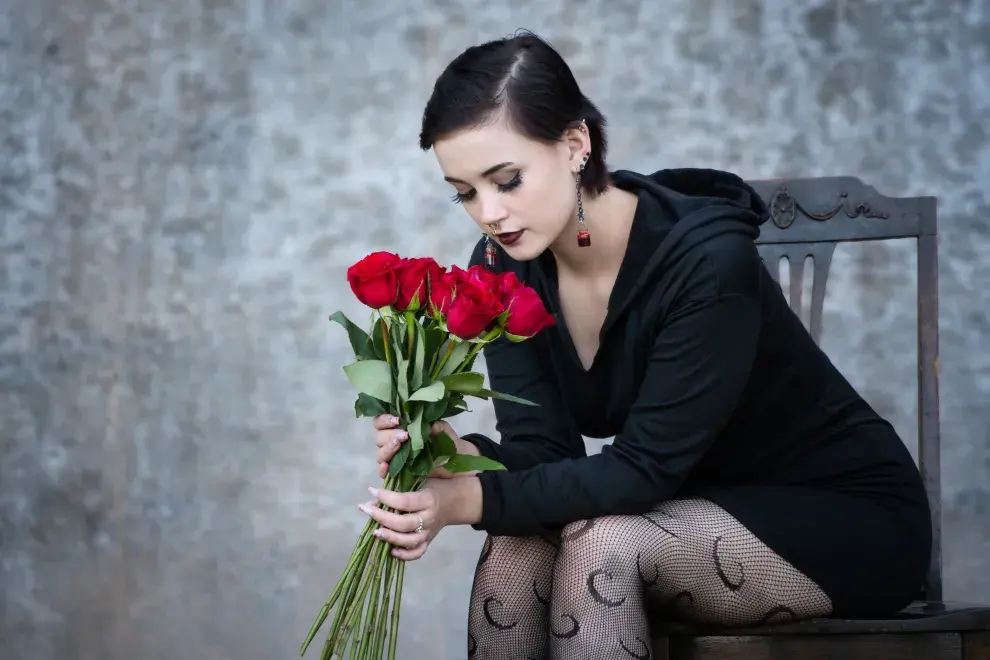 Foto de mujer oliendo rosas.