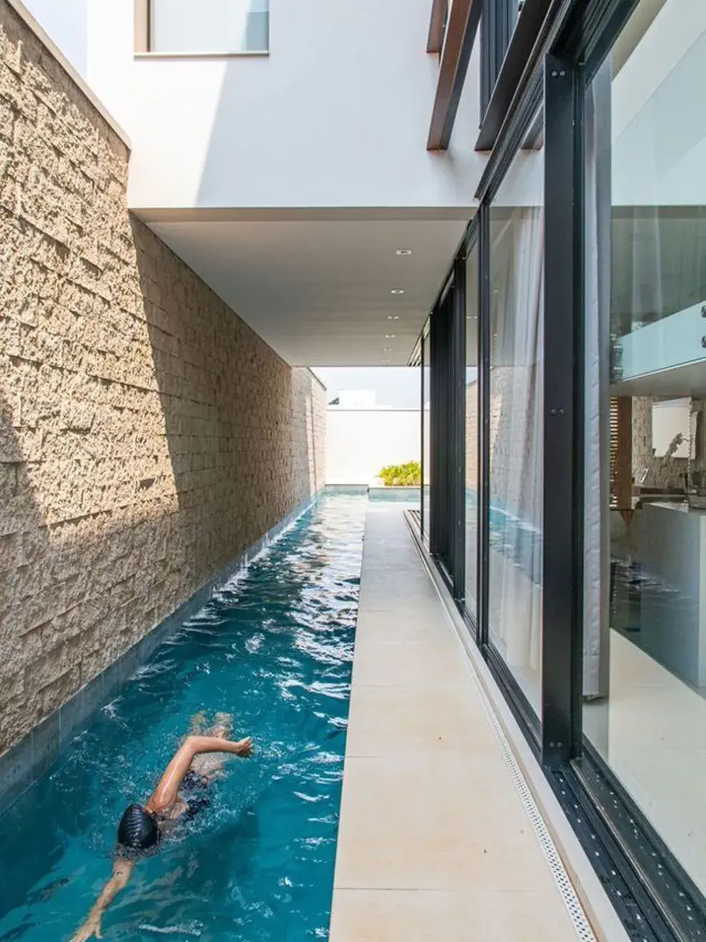 Una piscina estrecha junto a la pared de la casa