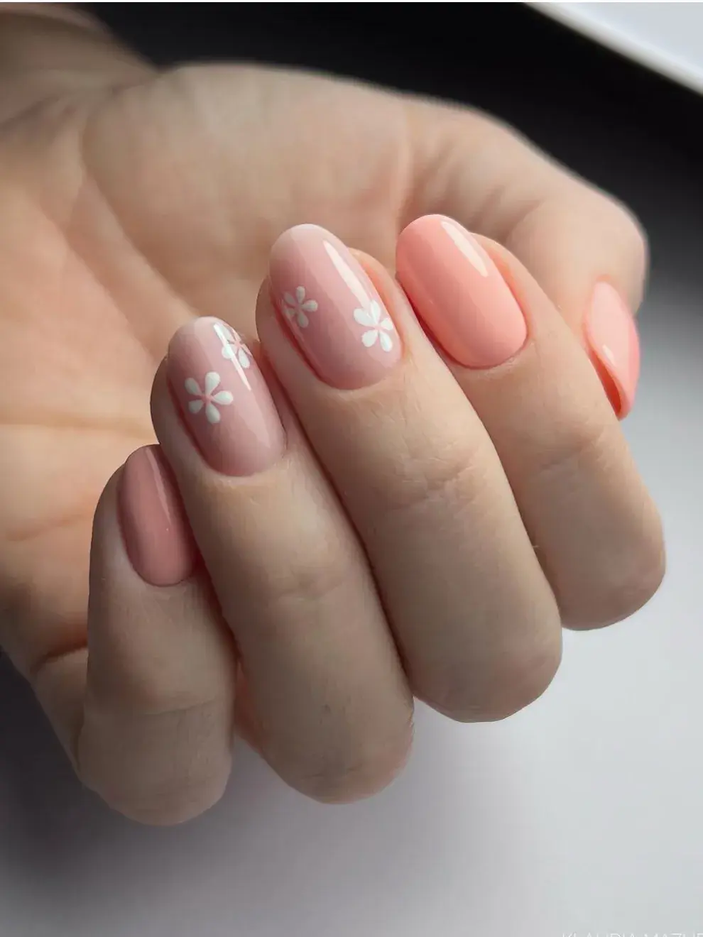 Combinar un fondo durazno con flores blancas o pastel crea una manicure campestre y femenina