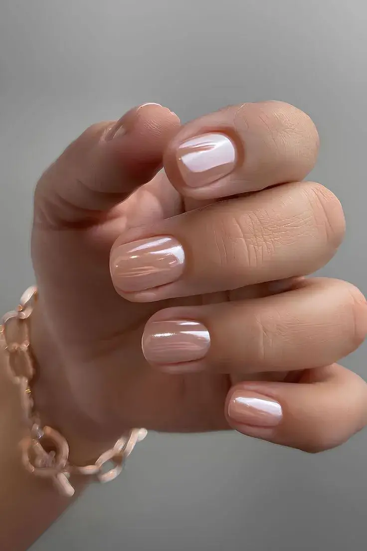 El famoso acabado “glazed donut” se adapta a las uñas cortas con bases rosadas o durazno y un brillo espejo sutil.