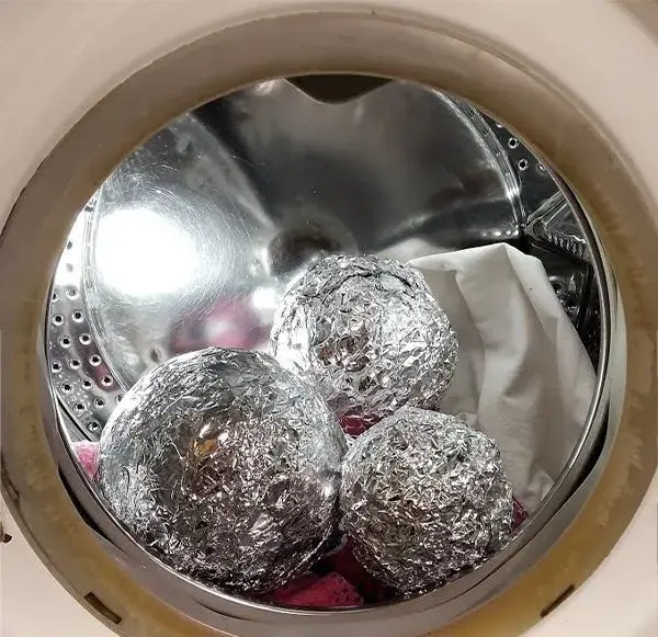 Foto de bolitas de papel de aluminio en el interior del lavarropas.