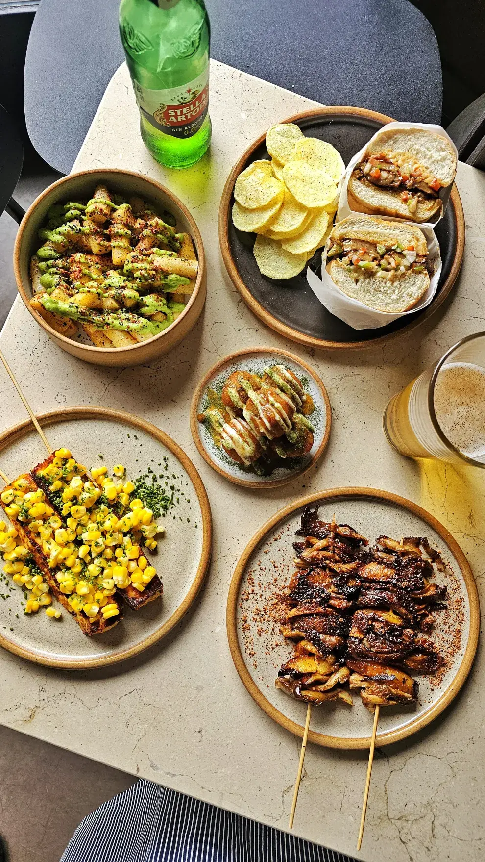 Mesa con platitos variados y una cerveza