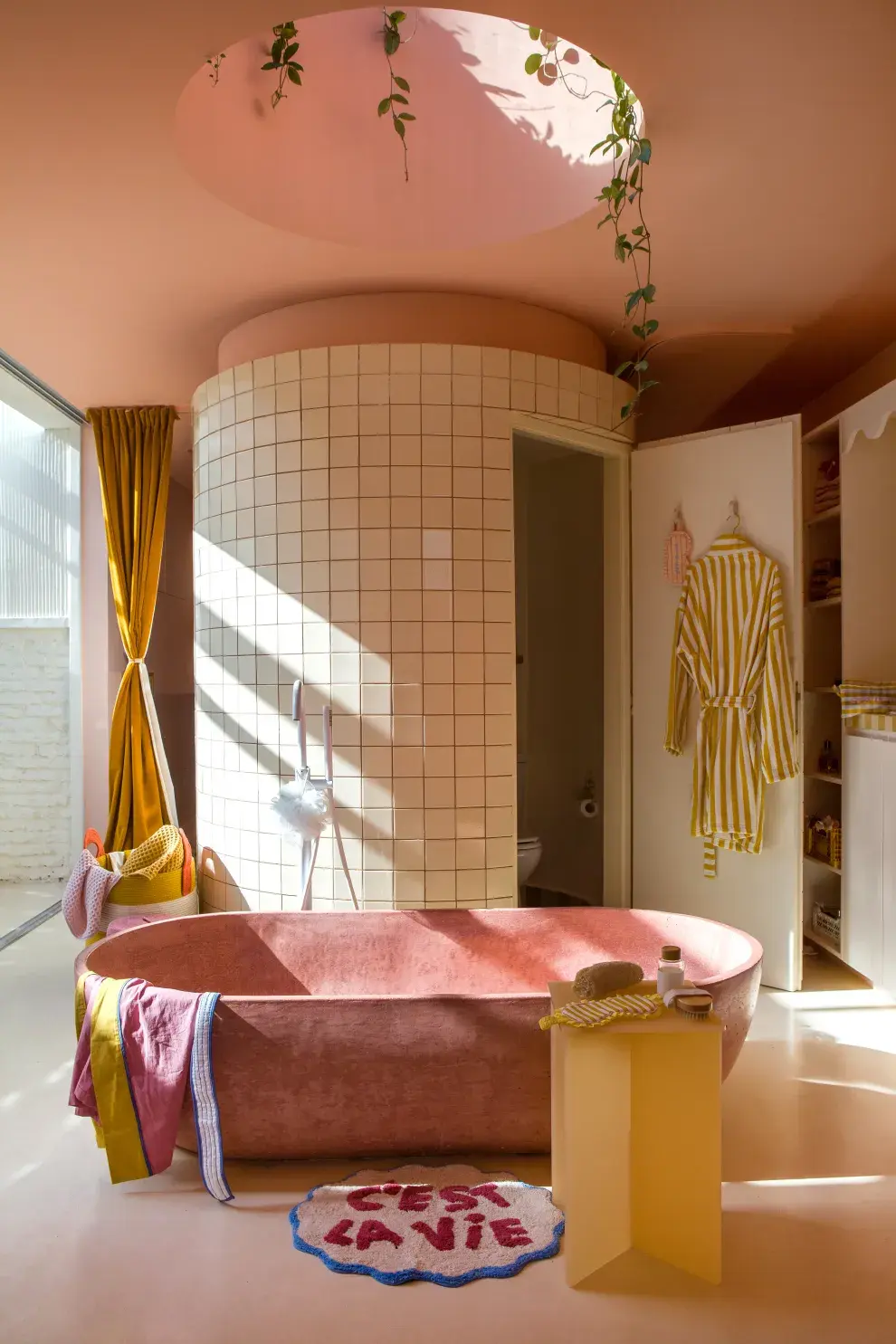 Sobre la bañadera color salmón, una claraboya baña de luz el ambiente y lleva a mirar el cielo. El volumen cilíndrico esconde la ducha