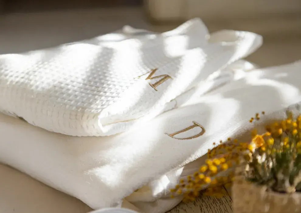 Dos modelos: bata de toalla tondosada aterciopelada, de textura suave y envolvente; y bata en tela waffle, con su característico relieve liviano. Disponibles en talles M, L y XL. Opción de personalizar con inicial bordada (costo adicional).  (MELISSA DOMIT desde $64.000,00)