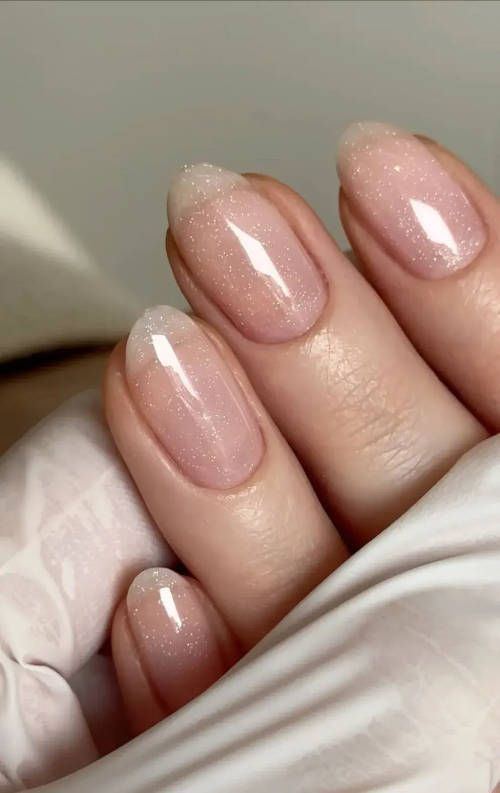 Minimalismo con un toque festivo: uñas neutras con destellos para Navidad y Años Nuevo.